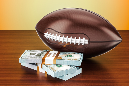 American football ball with dollar packs on the wooden table, 3D rendering の写真素材