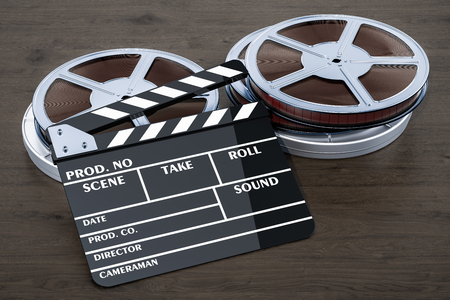 Cinema concept. Clapperboard with film reels on the wooden table, 3D renderingの写真素材