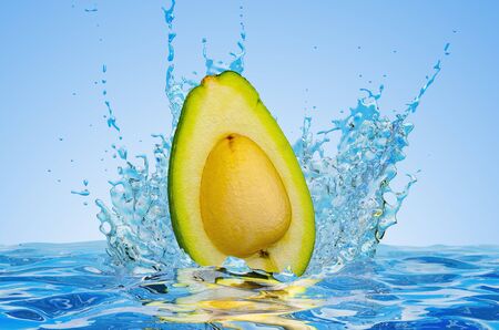 Avocado cut in half with water splashes, 3D rendering on blue background の写真素材