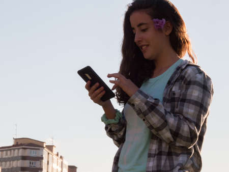Girl with mobile phone in hands looking at himの写真素材