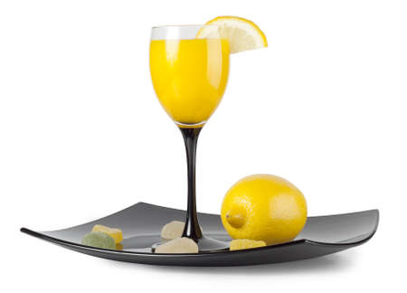 Glass goblet with the juice and lemon on a plateの写真素材