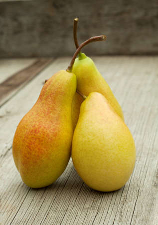 Three ripe pears with cuttings on a wooden backgroundの写真素材