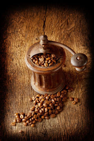 Antique coffee grinder with shiny seeds on a wooden backgroundの写真素材