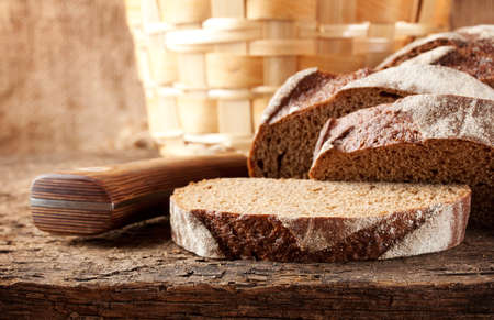Sliced brown bread with knife on wooden tableの写真素材