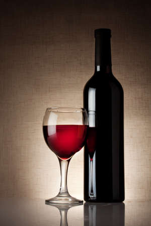 Glass of red wine with a bottle on burlap backgroundの写真素材