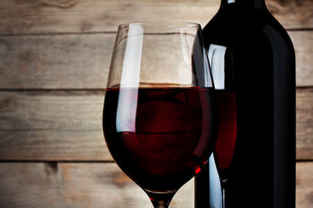 Detail of a glass red wine with a bottle on a wooden backgroundの写真素材