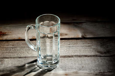 Empty glass beer mug on a wooden rackの写真素材