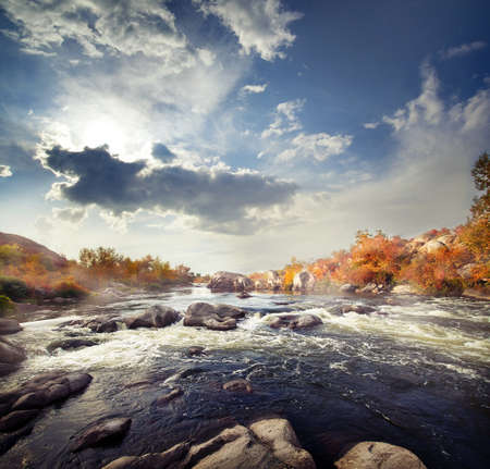 Rapid mountain river among stones and autumn treesの写真素材