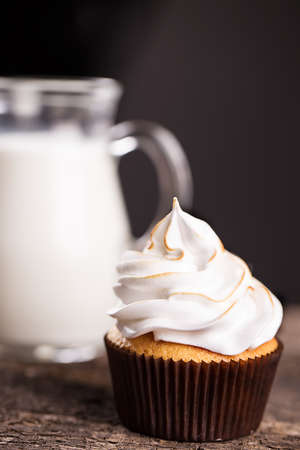 Delicious cupcakes with a carafe of milk on wooden tableの写真素材