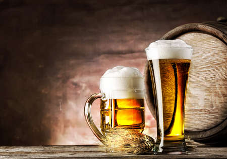 Mug and a glass of light beer on background of old barrelsの写真素材