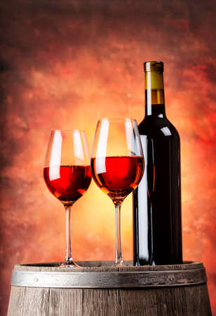 Bottle of red wine and two glasses filled with a wooden barrelの写真素材