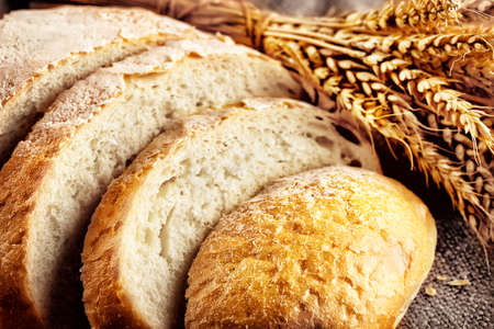 Loaf sliced white bread with ears wheat with a blurred backgroundの写真素材