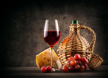 Glass of red wine and bottle braided on dark backgroundの写真素材