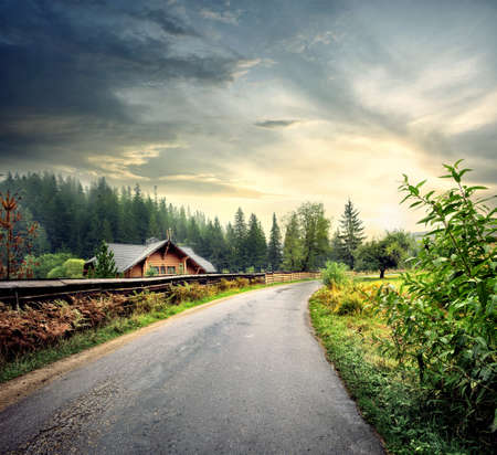 Asphalt road in the village under the cloudy skyの写真素材