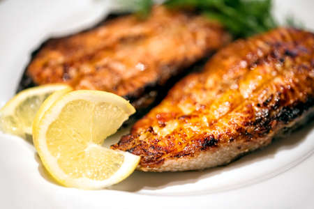 Slices of fried red fish on white plate shot with blurred backgroundの写真素材