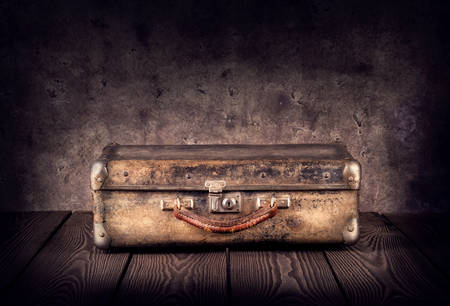 Old shabby suitcase on dark background