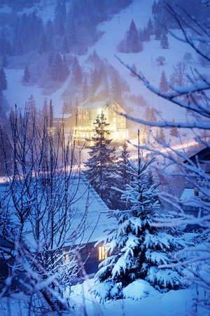 Glowing houses in winter mountains at nightの写真素材