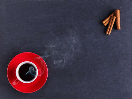 Coffee and cinnamon sticks on black tableの写真素材