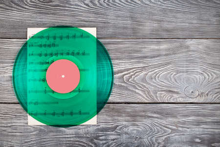 Vinyl record and music notes on wooden backgroundの写真素材
