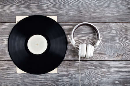 Vinyl record and headphones on wooden background