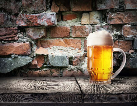 Mug of light beer foam on the brick wall backgroundの写真素材