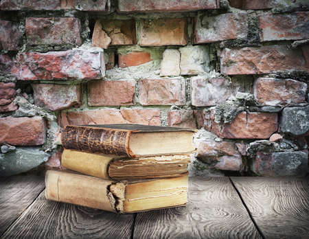 Stack of books on wooden table on background of brick wallの写真素材