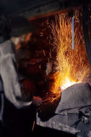 Blacksmith working near burning hearth shot with selective focus