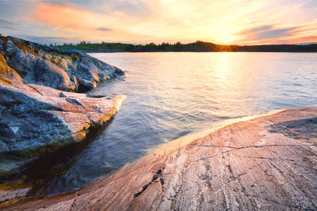 Rocky shore in the water at sunsetの写真素材