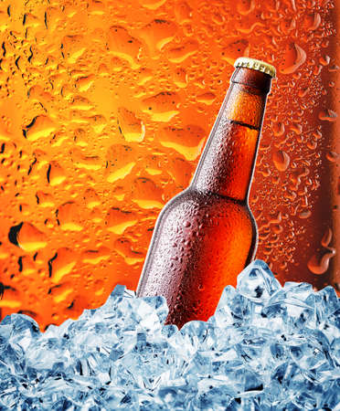 Brown bottle of beer in the ice on brown background with dropsの写真素材