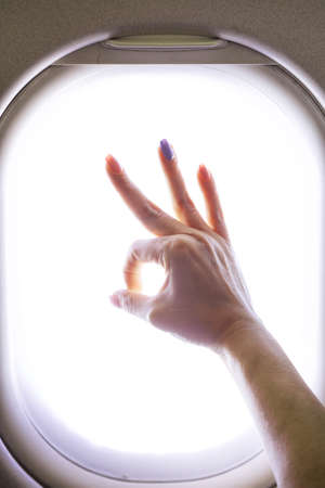 Female hand in gesture of ok in the airplaneの写真素材