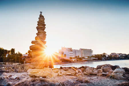 Cairn on seashore shot in front of bright sun