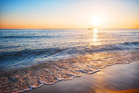 Sea sandy beach with the surf at sunsetの写真素材