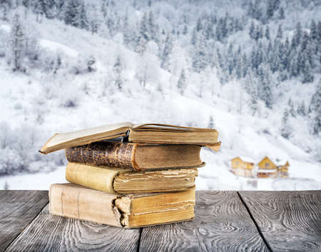 Old books on the wooden table against the background bokeh winter mountainsの写真素材