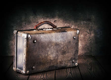 Old leather suitcase on a wooden table with dark backgroundの写真素材