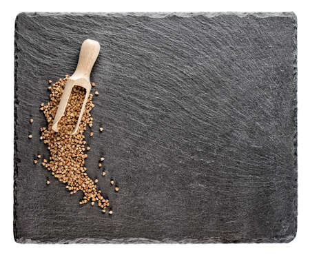 Buckwheat groats with wooden spoon on slate blackboard isolated on white backgroundの写真素材