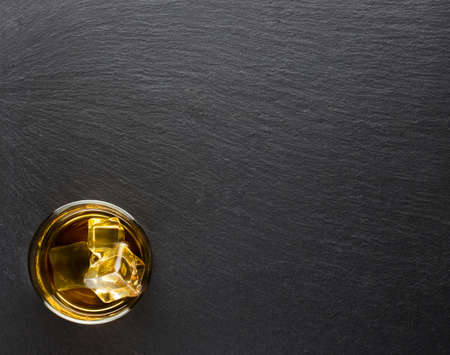 Glass of whiskey with ice on a black background shot from aboveの写真素材
