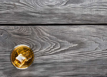 Wooden background with a glass of whiskeyの写真素材