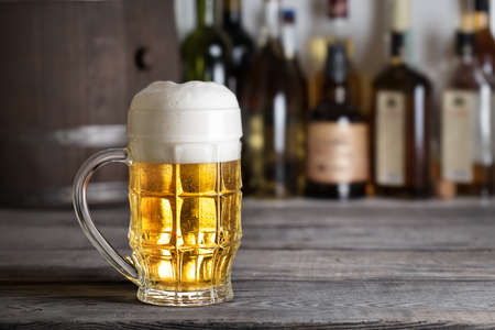Large glass of light beer with foam on bar counterの写真素材