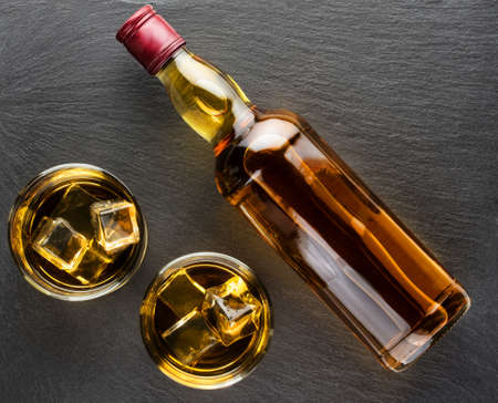 Two whiskey glasses and a bottle on dark backgroundの写真素材