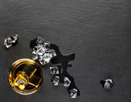 A glass of whiskey with ice and melted iceの写真素材