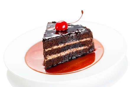 Dark cake with a cherry and syrup isolated on a white background