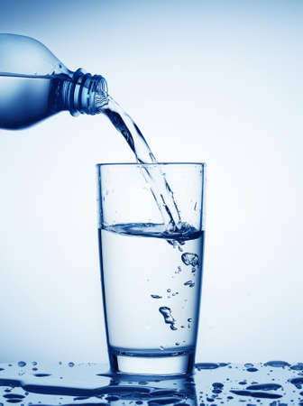 Water flowing from bottle into a glassの写真素材
