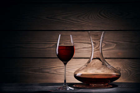 Decanter and glass with red wine on a wooden tableの写真素材