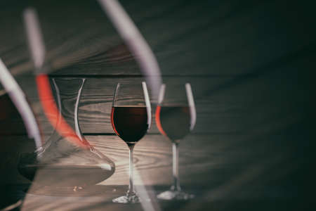 Two glasses and decanter of red wine on a dark wooden background. Double exposure, toning.の写真素材