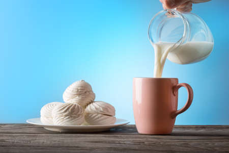 Milk poured from a jug into a cupの写真素材