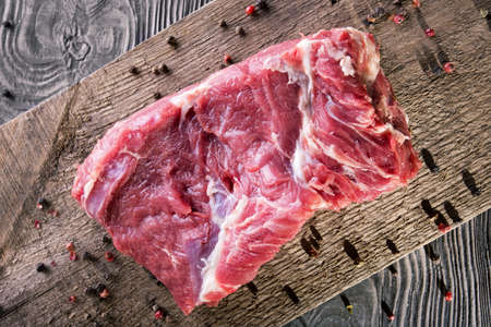 A piece of fresh raw meat with pepper on a wooden boardの写真素材