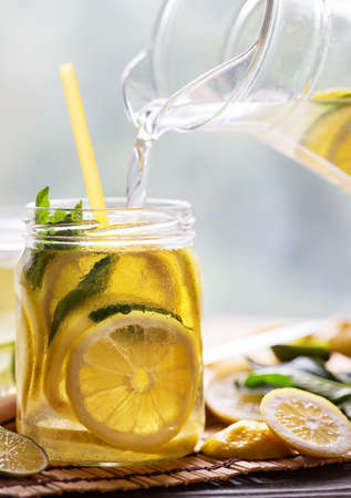 Lemonade pouring from the jug into the jar. Reinforcing and refreshing cold drink. The concept of...