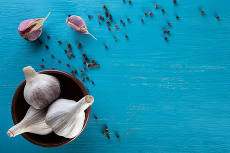 Garlic in a plate and pepper on a blue wooden table. Spice. Food background. The concept of healthy food.の写真素材