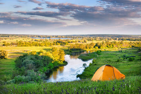 Orange tent on the high bank of the river. Summer landscape. The concept of freedom and travel.の写真素材