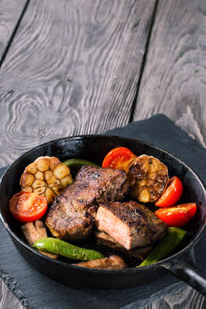Slightly fried beef steak with vegetables on cast-iron frying paの写真素材